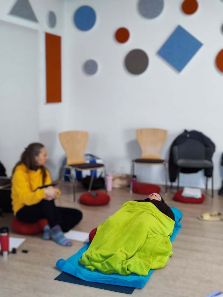 Person liegt unter einer grünen Decke in Therapie.